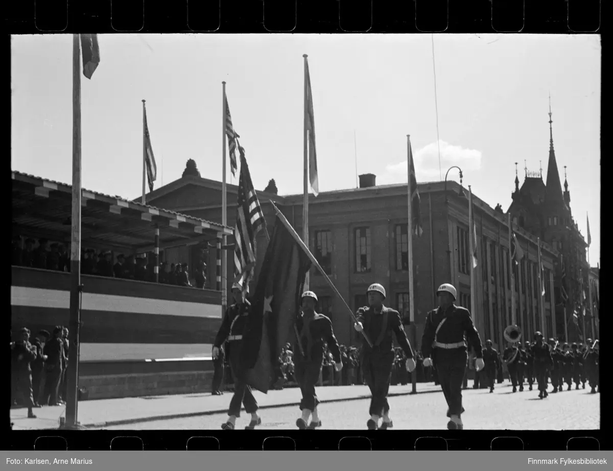 Foto av Amerikansk militær politi i hvit hjelm (US Military Police Corps) i parade på de alliertes dag den 30. juni 1945 i Oslo (The Allied Forces day). 

Bak militærpolitiet kan man se the 1st Army band (også amerikanere)

I bakgrunnen kan man se en tribune der flere offiserer står å ser på paraden. Tribunen var satt opp foran Universitetsplassen på Karl Johan 