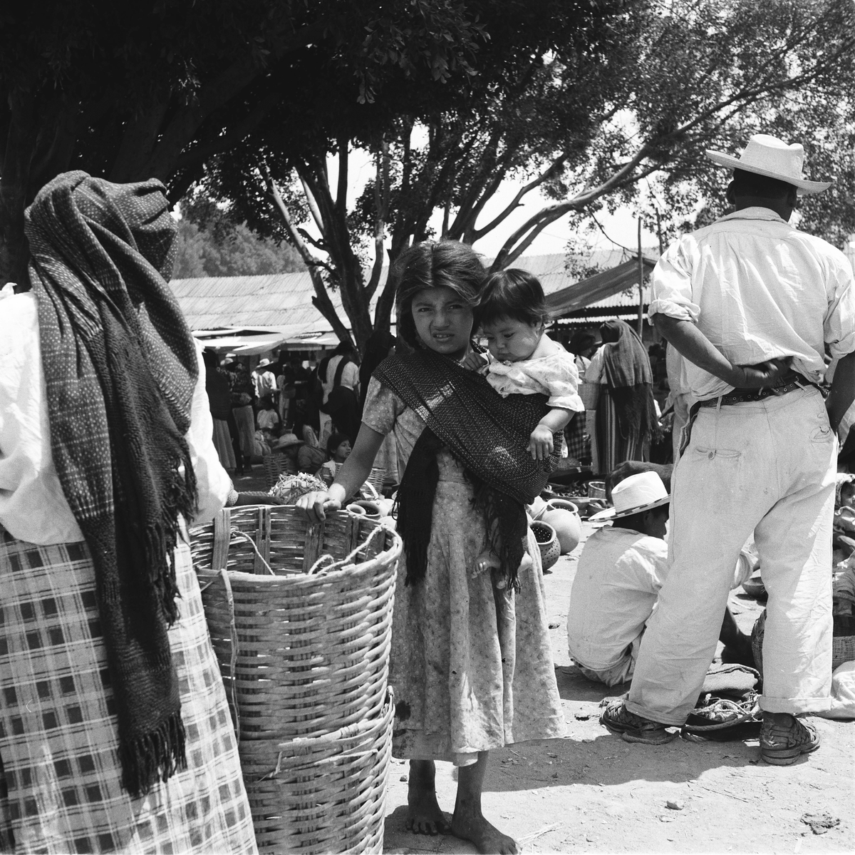 Barbeint kvinne på markedet med ett barn på skulderen.
