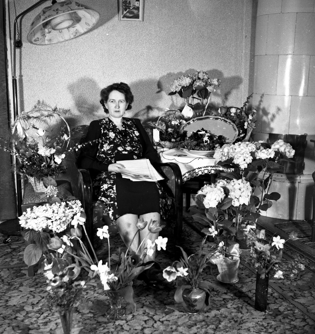 Kvinna sittandes vid blomsterbord.