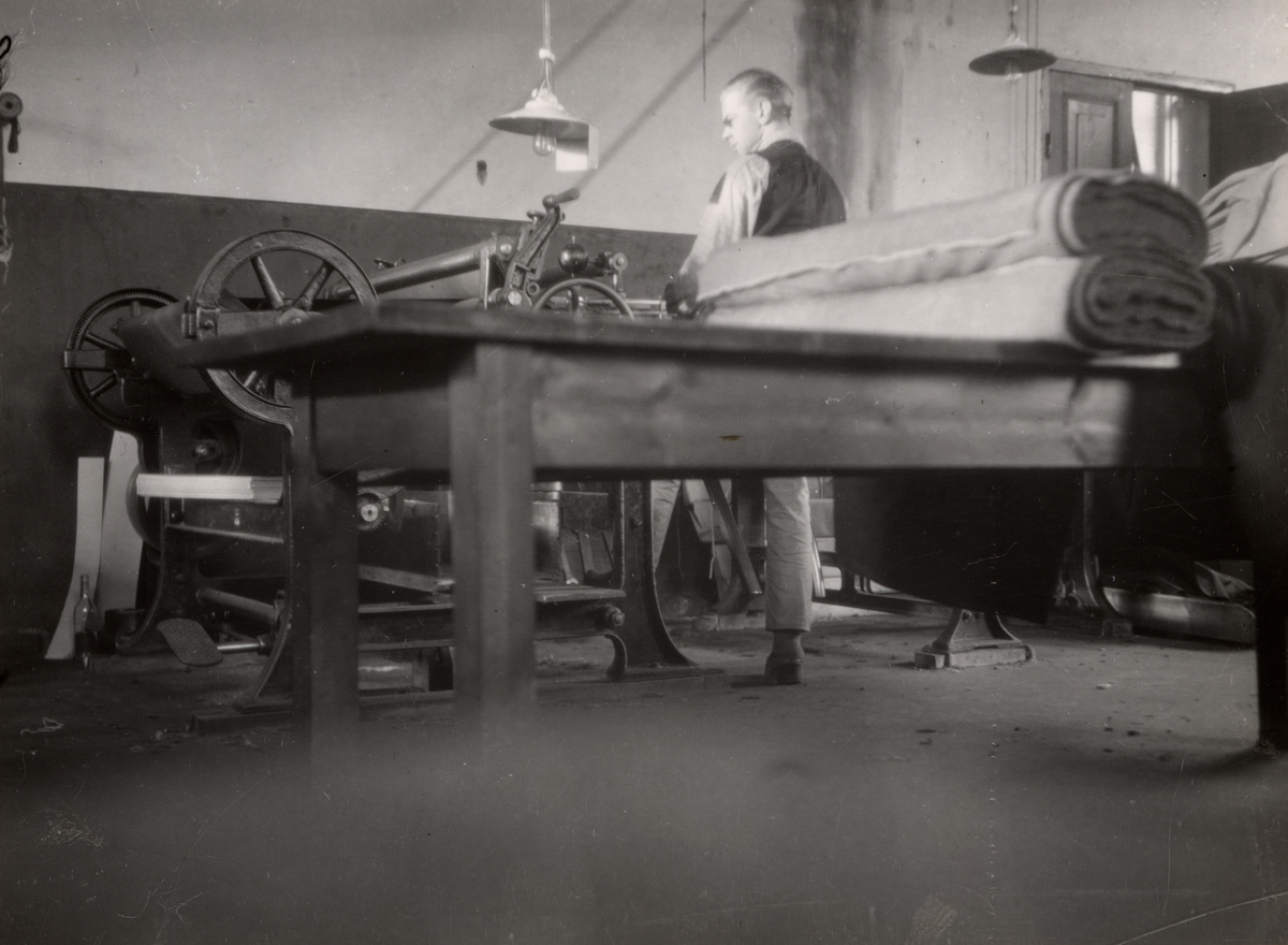 Abrahamsons Berednings Aktiebolag. Dekateraren Utter sysselsatt med att rulla styck på hopslagnings- och mätmaskinen på Kvarngatan 39, 1930.
