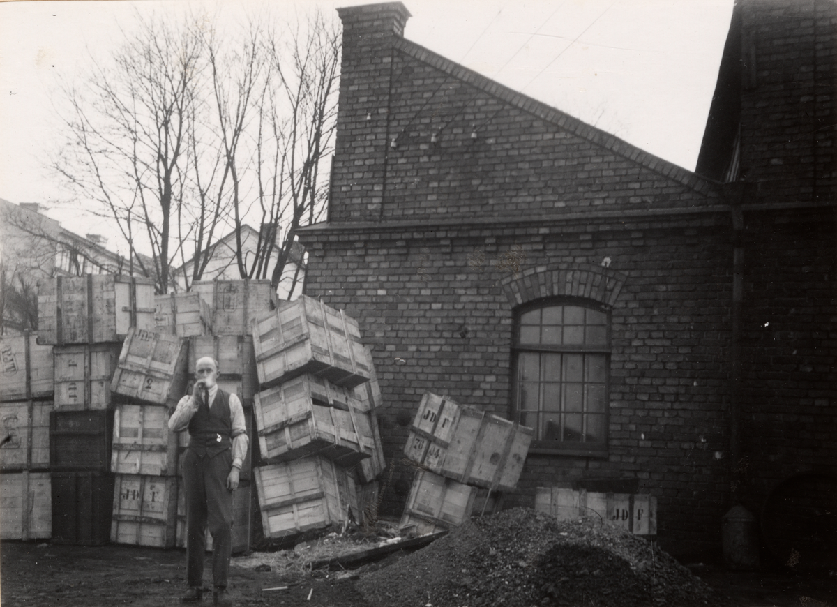 Abrahamsons Berednings Aktiebolag. Pressare Eliasson tar sig en för tillfället tillåten rökpaus på fabriksgården på Kvarngatan 39. Tomlådor efter kamgarn, 1930.