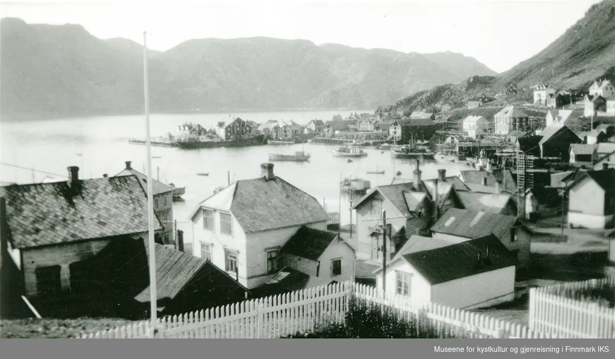 Honningsvåg. Indre havn med bebyggelse og flere båter. I midten bak ser man Holmen med dampskipskaia. Ca. 1930.