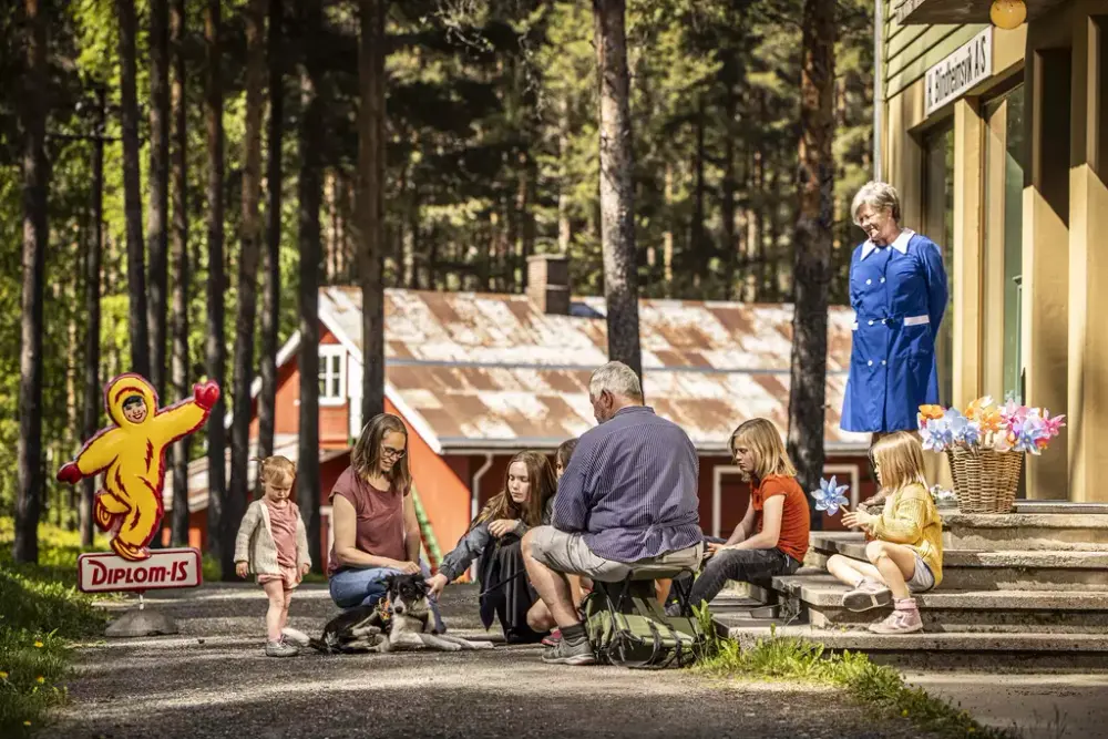 Bildet viser besøkende i museumsparken foran Blindheimsvik landhandel i museumsparken.