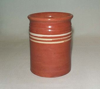 Rödbrun vas både på in- och utsida av lergods med gula ränder på utsida.