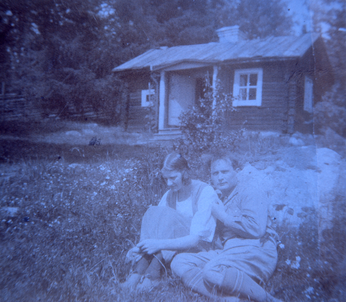Albert Viksten och hans första fru i gröngräset i sluttningen nedanför ett litet torp.