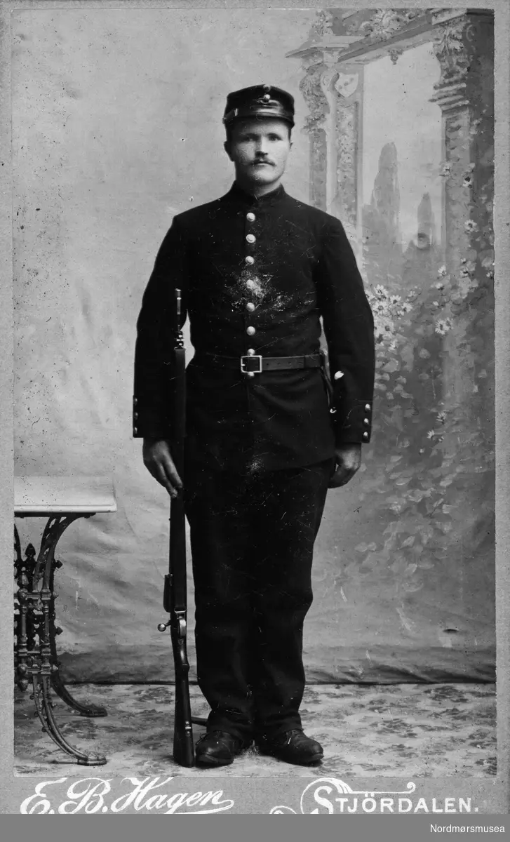 Portrett av en mann i uniform; Soldat med gevær. Det er ukjent hvem vi ser på bildet, men har trolig forbindelser til Kristiansund.