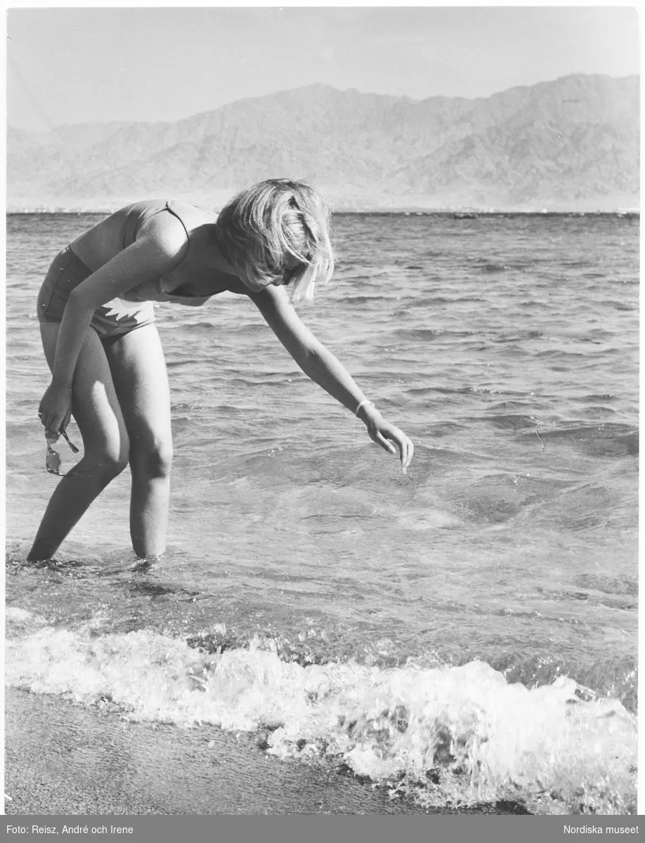En flicka böjd över vattnet i havet.