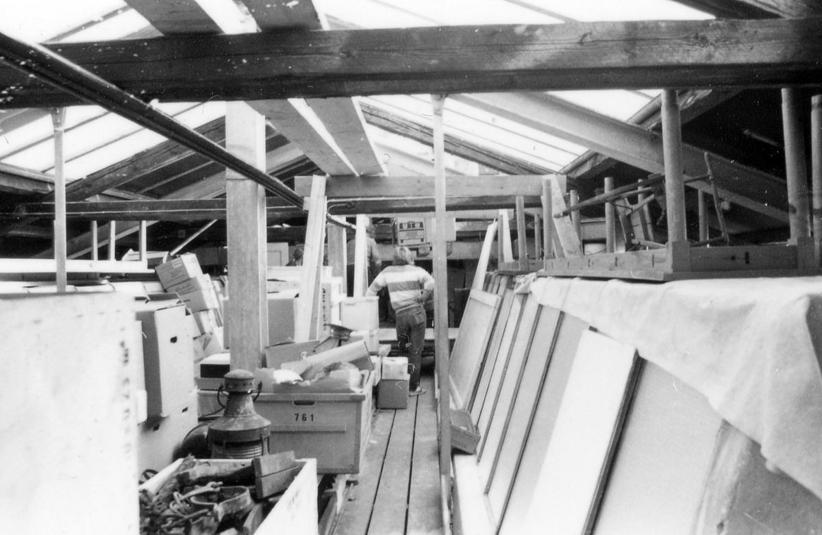 Museivinden, föremålen är nedpackade i lådor, ställda på pallar, lyfts med kran genom öppning i taket. 
Från reparationsarbetena den 1 september 1983.