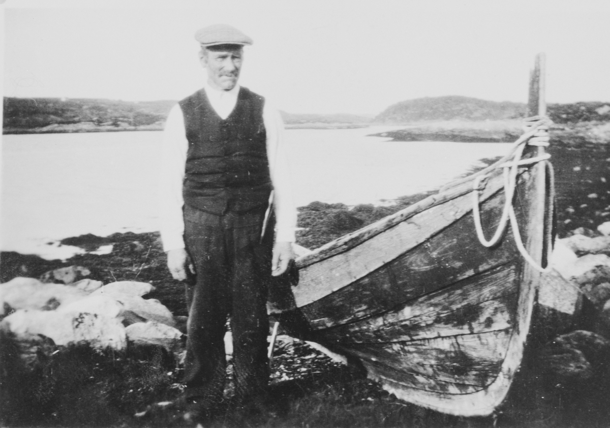 Jørgen Edvard Severinsen Vollan står i fjøra ved siden av en robåt