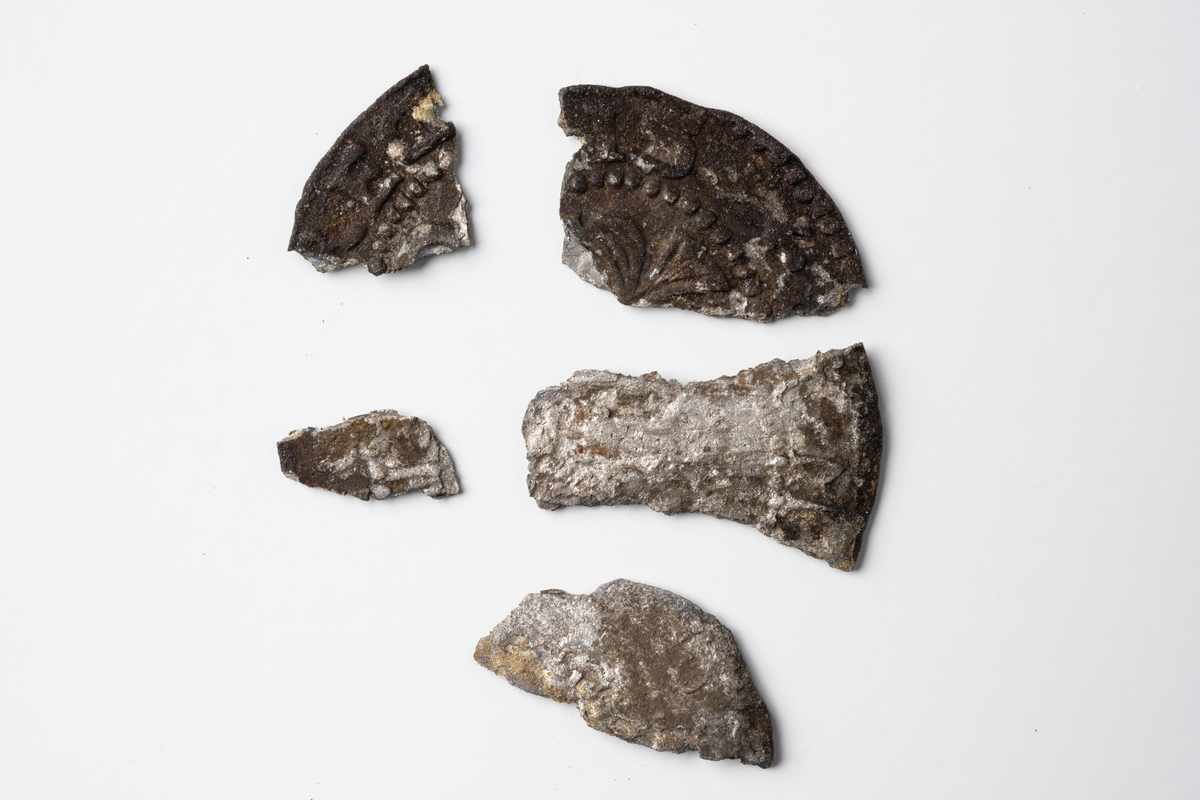 Fem fragment av ett ettöres silvermynt från 1600-talet. Samtliga fragment från myntet finns inte kvar.