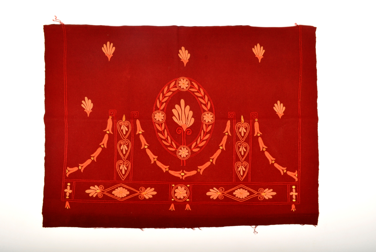 Rødt tekstil dekorert med broderi i ulike rød og oransje farger.