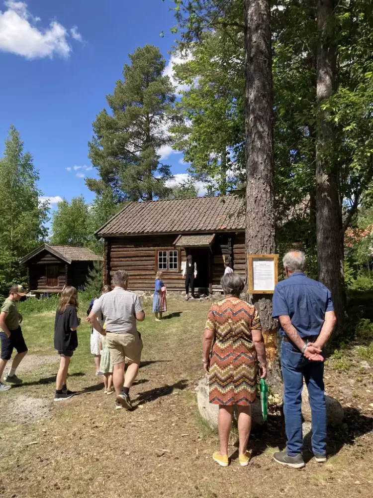 En gruppe mennesker står ute på friluftsmuseet.