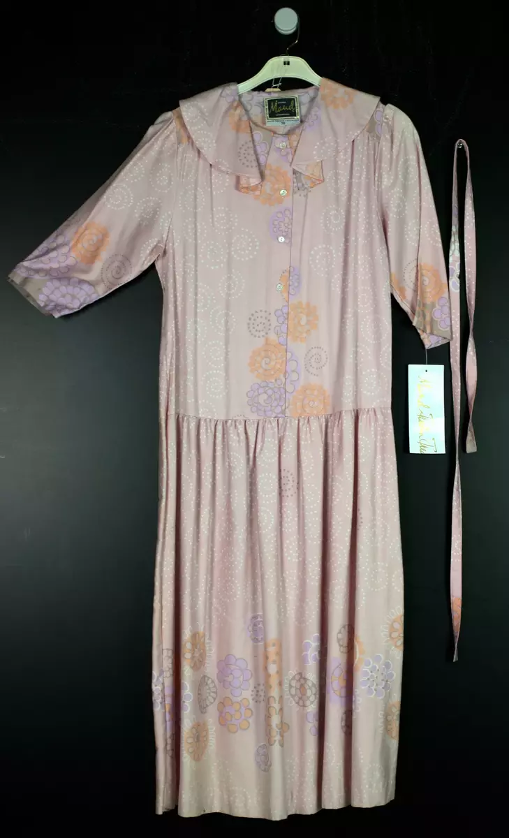 Ljusrosa klännig i textilmönstret Korall. Stor bluskrage, lågt sittande midja, klockad kjol samt tillhörande skärp.