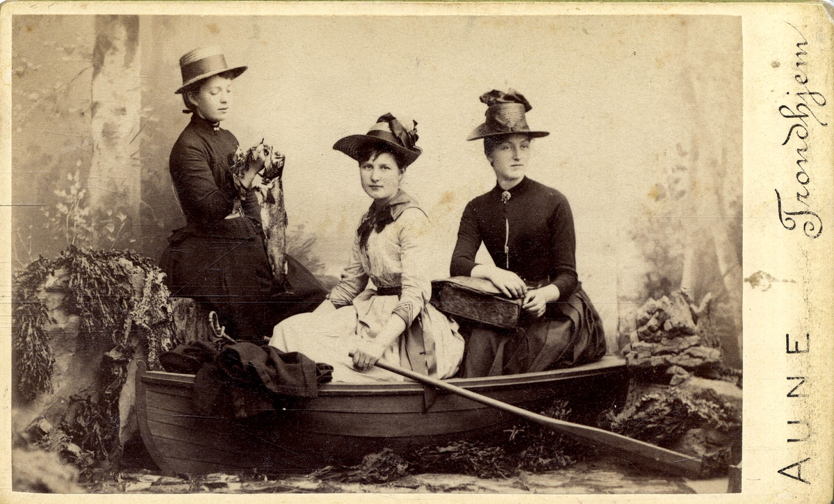 Studioportrett av tre kvinner i robåt.