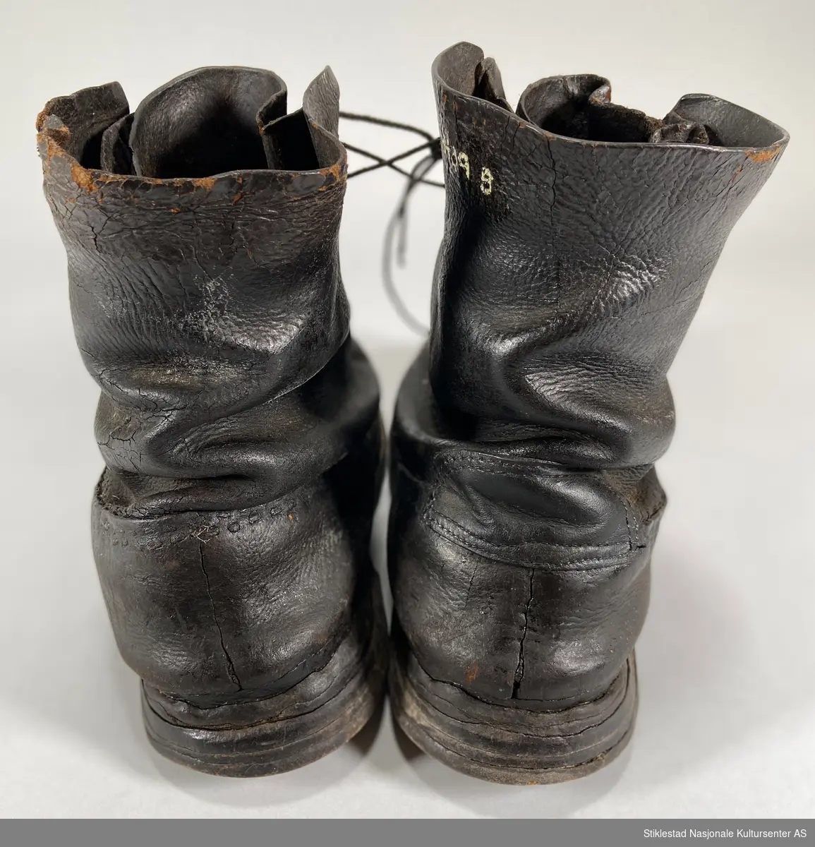 Et par lauparsko/skinnsko med nyere snøring. Skaftet har maljer i metall. Påsatt ekstra lærsåle på hælen. Skobespar på begge hæler. Underlær er sydd sammen med overlæret. Uforet sko.