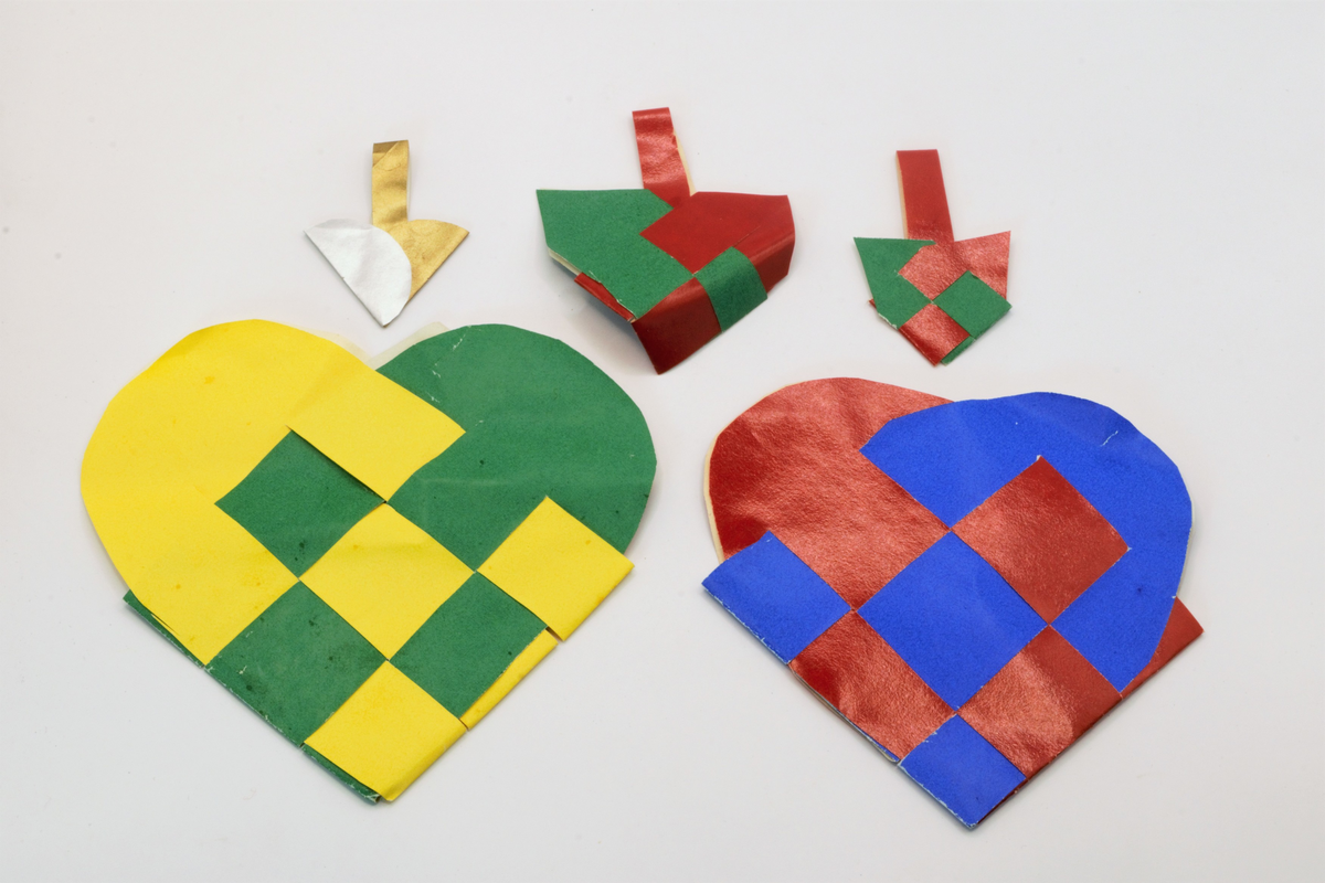 Fem flettede hjerteformede julekurver i ulike størrelser og farger.