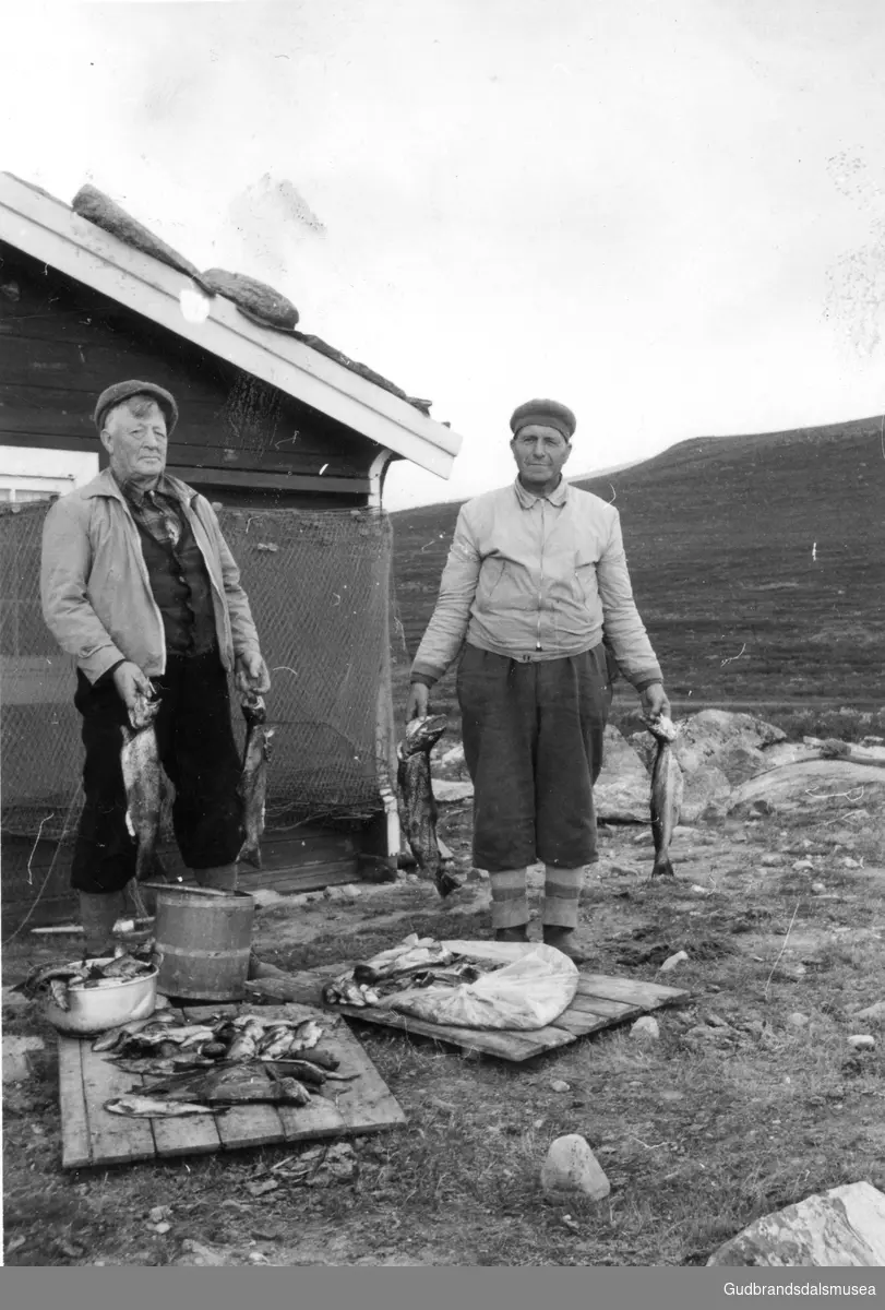 F.v.: Torvald Skrinde (f. 1895) og Ola Hagen (f. 1900) med fiskefangst ved hytta til nordgard Skrinde på Honnsjoen