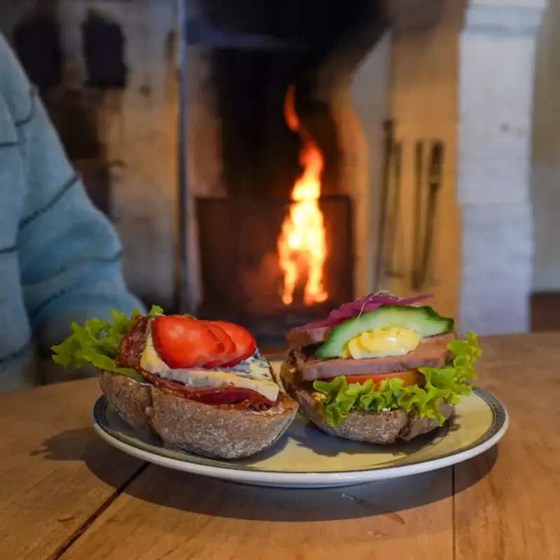 Rundstykker med pålegg. Peisen ses i bakgrunnen. 