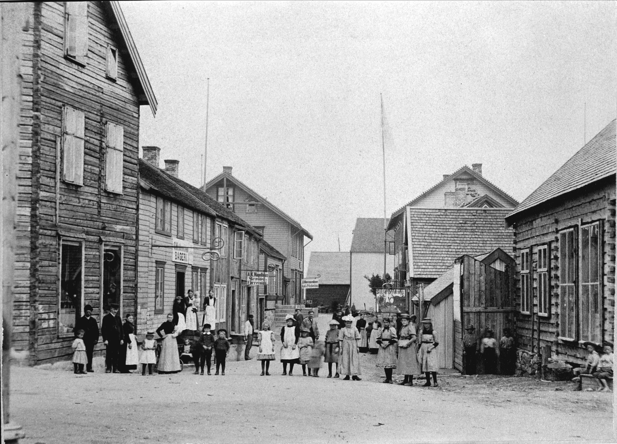 Kvinner, barn og et par menn stilt opp på tvers av "Gågata" (Rikard Kaarbøs gate).