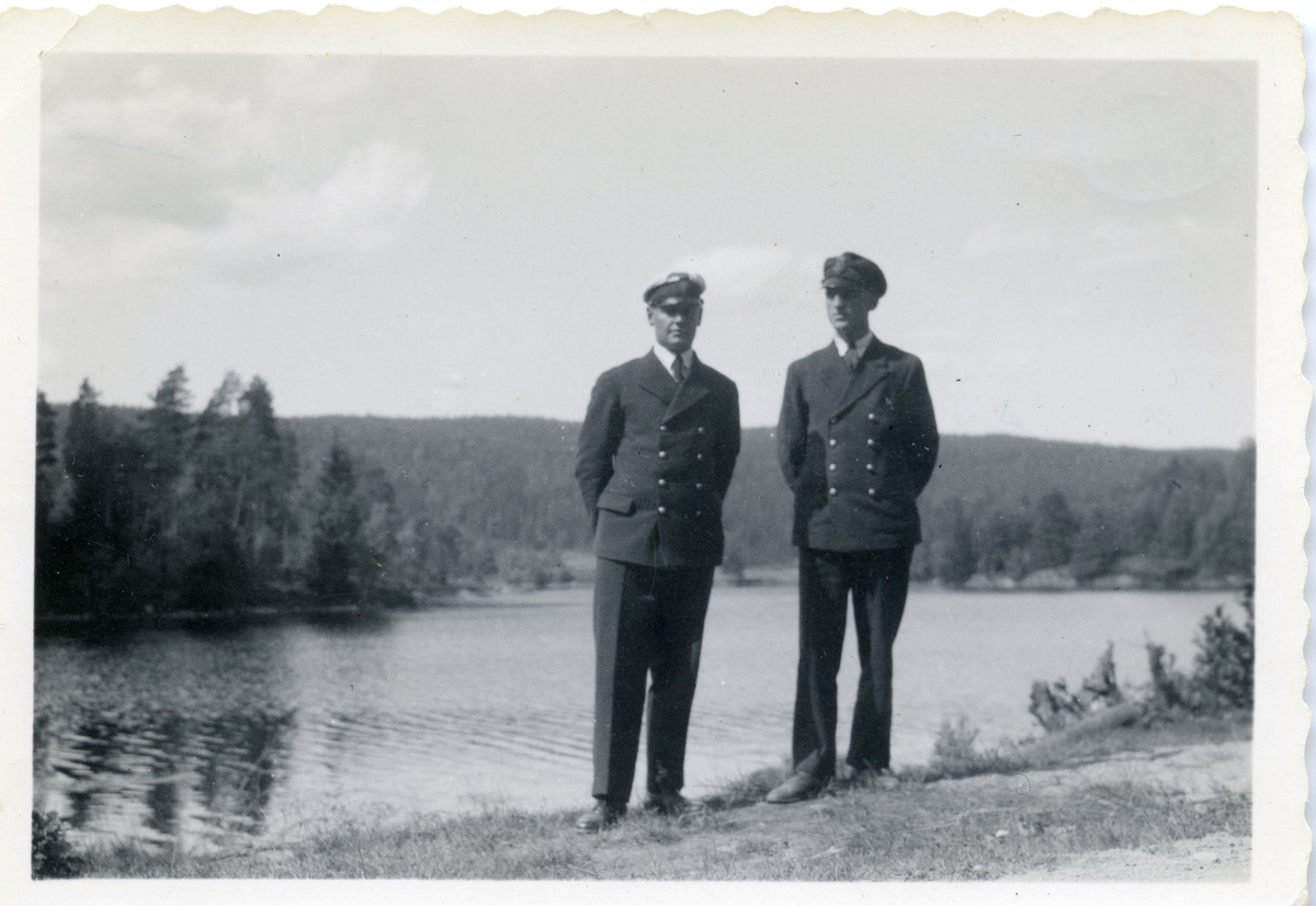 Två män i [tull]uniform framför vattendrag, Harald Sundling till vänster.