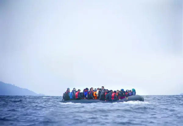 Bildet viser flyktninger i en stor gummibåt ute på havet.