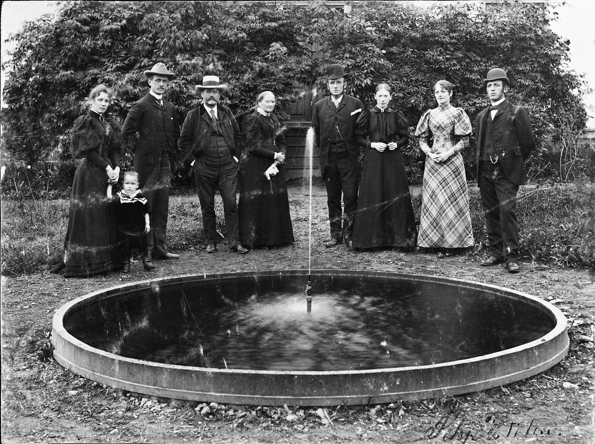 Gruppebilde. Personer ved ei fontene i en hage. Ingen info foreligger.