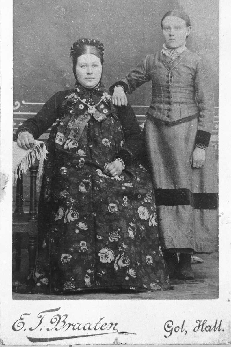 Portrett av ei dame med bunad og ei dame i kjole og sølje.