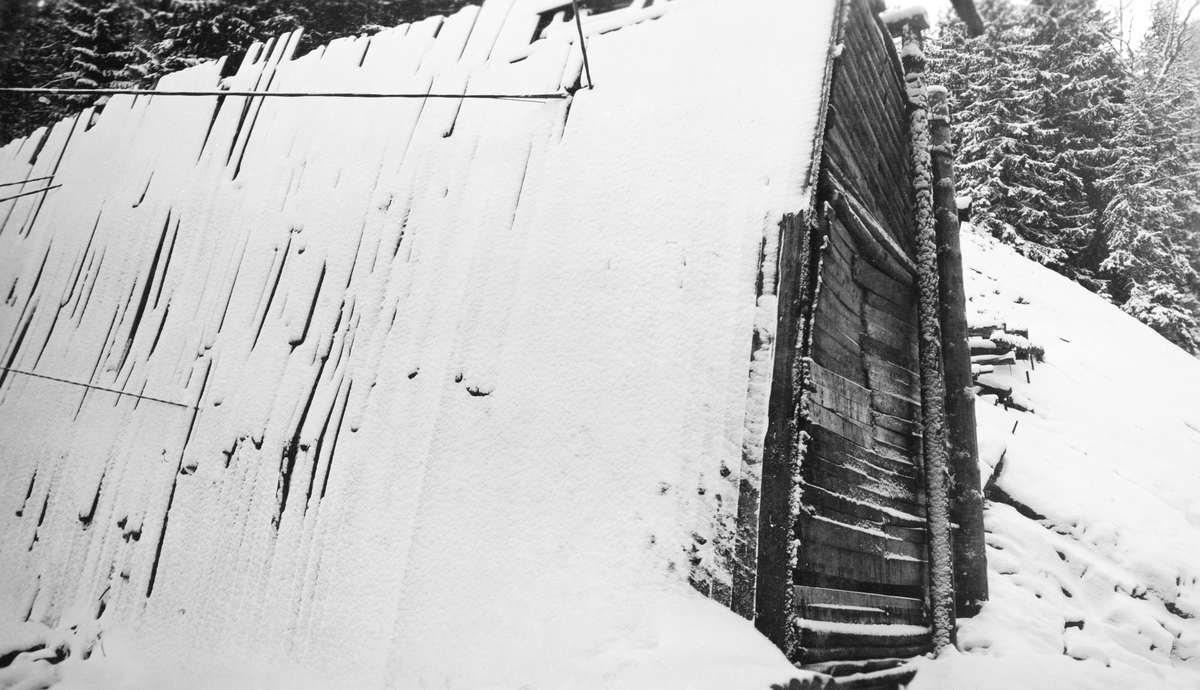 Et av de siste bildene av den «gamle» Sølvstudammen i Ågårdselva i Tune i Østfold, fotografert like før arbeidet med å rive dammen og reise en ny startet. Fotografiet er tatt på nært hold mot en åpning i dammen, som hadde et trapesformet tverrsnitt, og var bordkledd. Bordkledningen var snødekt. Ågårdselva er et cirka fem og en halv kilometer langt vassdrag som renner fra den nordvestre enden av Isnesfjorden (Vestvannet) i Nedre Glommas vestre løp, sørvestover gjennem berglendt terreng mot innsjøen Visterflo. Høydeforskjellen mellom Isnesfjorden og Visterflo er på bortimot 25 meter. Ågårdselva har tre fossefall, det øverste her ved Sølvstu, deretter ved Valbrekke og nederst ved Solli. Behovet for den dambygginga vi ser på dette fotografiet var forårsaket av selskapene Borregaards og Hafslunds inngrep i Glommas østre løp, hovedløpet, som i lavvannsperioder gjorde det svært vanskelig å få tømmer som skulle til bedrifter nedenfor Sarpsfossen via Mingevannet, Isnesfjorden og tømmertunnelen til Eidet gjennom det trange sundet ved Trøsken. Dette forsøkte man å løse ved å heve vannspeilet i Isnesfjorden med en dam som skulle plasseres 10-15 meter ovenfor den eksisterende dammen ved Sølvstufossen. Se mer informasjon under fanen «Opplysninger».