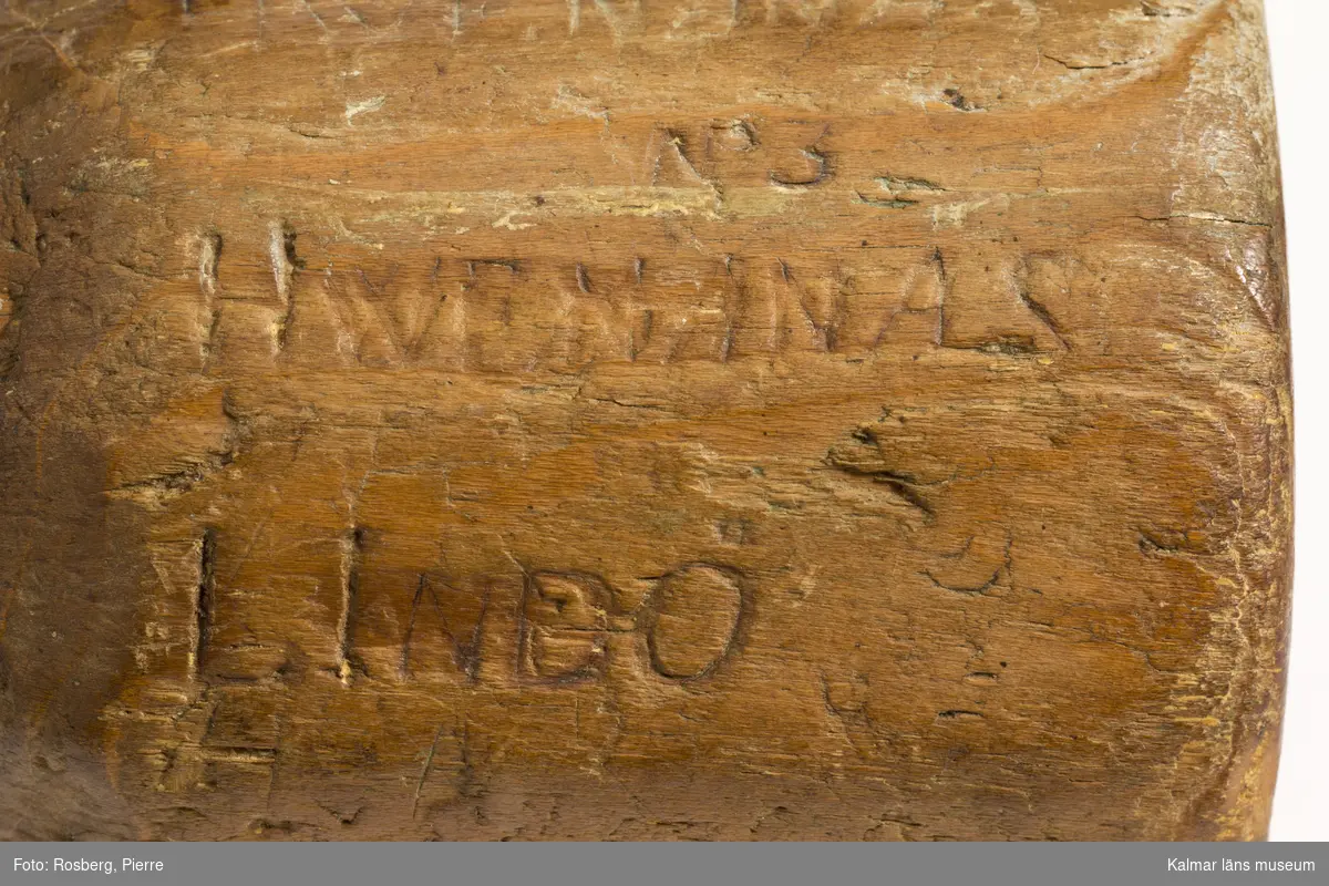 KLM 11461. Byklubba. Tillverkad av trä. Tiokantig klump med bynamnen på respektive fält. I botten text, en vers inristad av tillverkaren samt hans initialer, bomärke LR,  Min vandringstid. . . år 1800 (eller 1806).