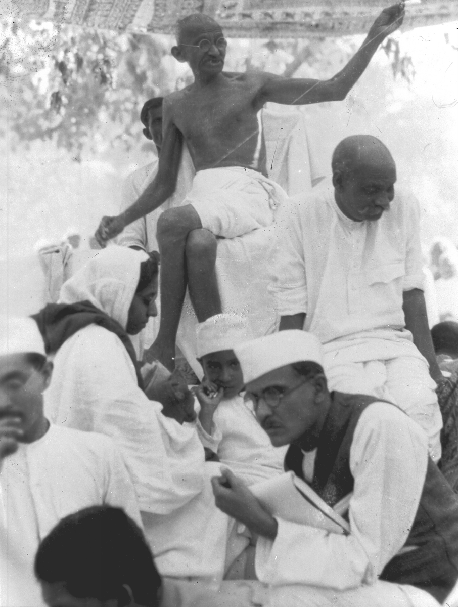 Gandhi som spinner omgitt av mennesker i sitt hjem.  Fotografi samlet i forbindelse med Elisabeth Meyers reise til India 1932-33.