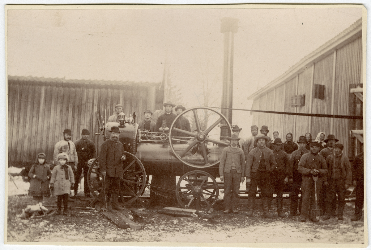 Foto av arbeidere foran en lokomobil. 

Foran som nr. 5 fra venstre står byggmester Nestor Malthe (med skjegg og spaserstokk). Foto tatt i 1884