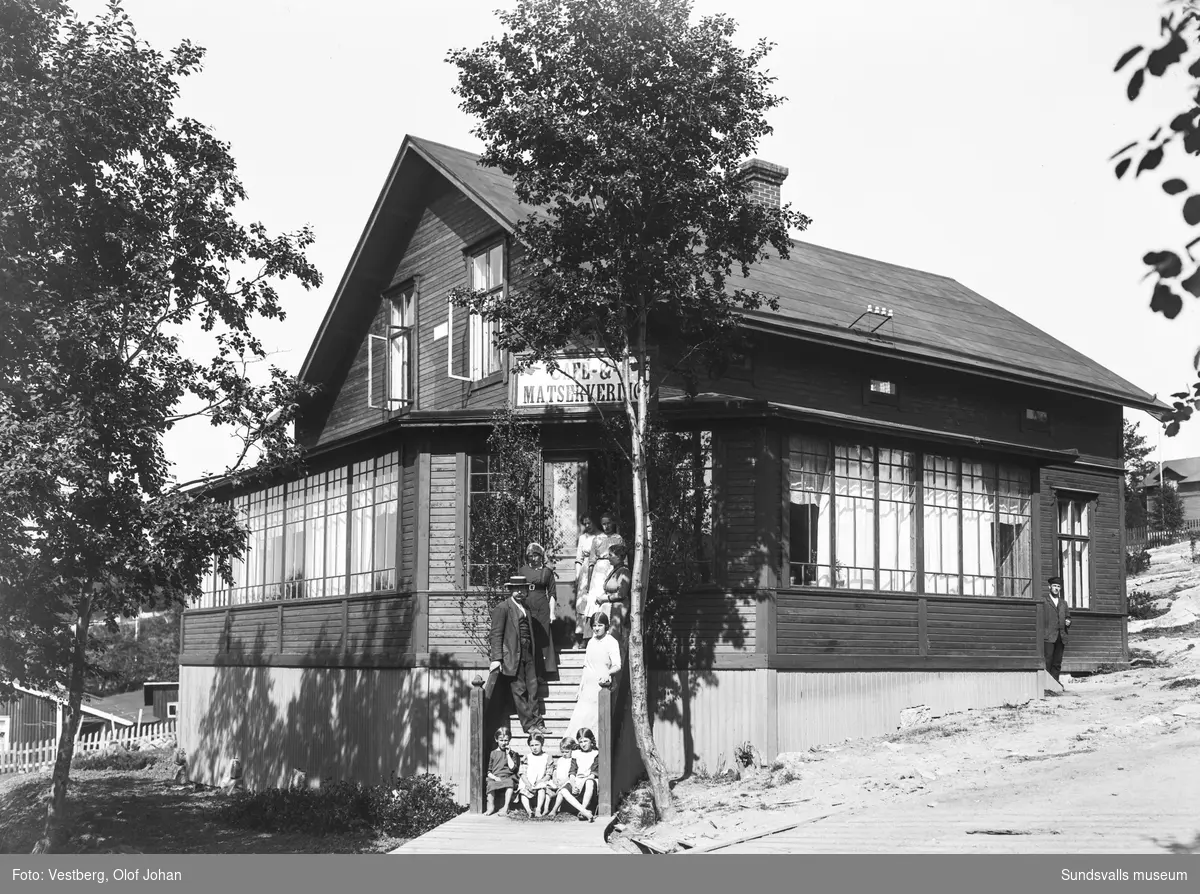 Två bilder med ett hus med glasveranda, ingång på hörnet och skyltat med "Café- & Matservering". Vuxna och barn poserar på trappen. Den andra bilden är något tidigare, innan skylten kommit upp, och en annan årstid. Där syns också serveringspersonal i fönstret.