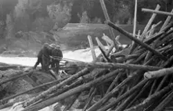 Fløtere i arbeid med å løsne tømmerhaugen som hadde bygd seg