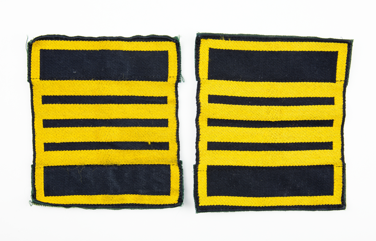 Ärmmatta, överstelöjtnant, med invävd gradbeteckning i gult på svart botten. Två stycken. På baksidan fastsydda kardborreband.