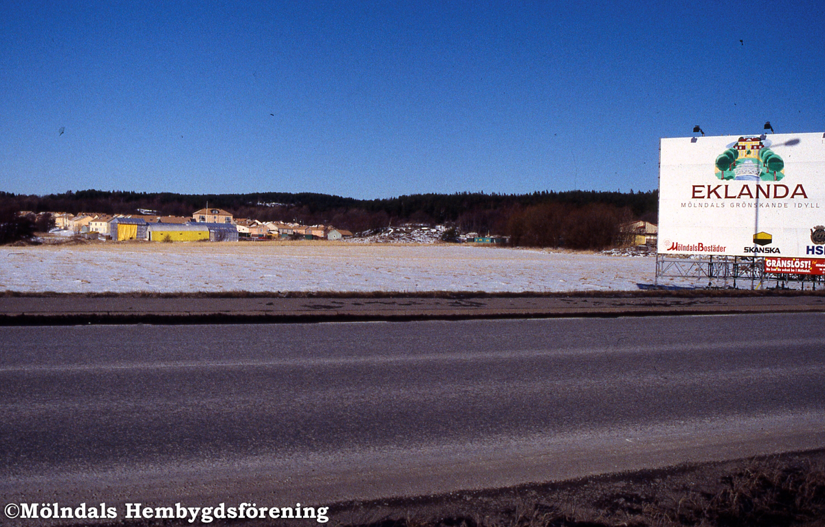 Eklanda i Mölndal, januari 1994. Till vänster den nya bebyggelsen, till höger reklamskylt om området.