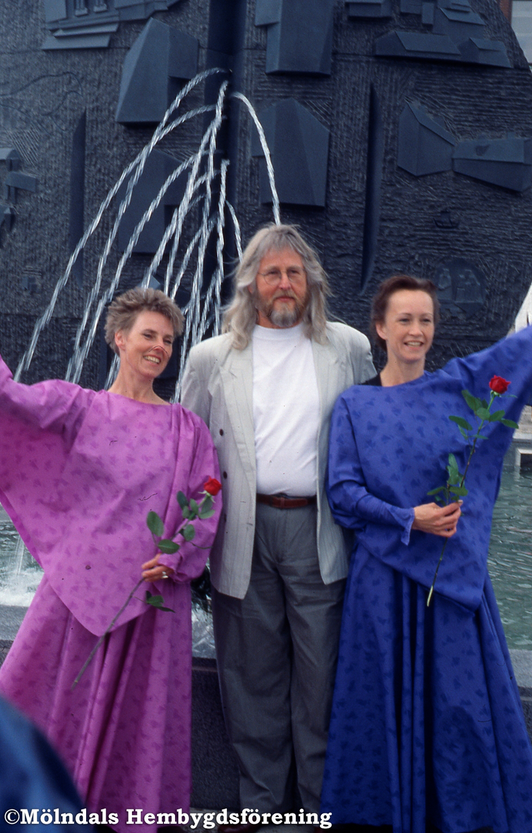 Stadshusplatsen i Mölndal, den 17 maj 1991. Konstverket Faesbiaergha invigs. Konstnären Roland Andersson och två kvinnliga dansare framför konstverket.