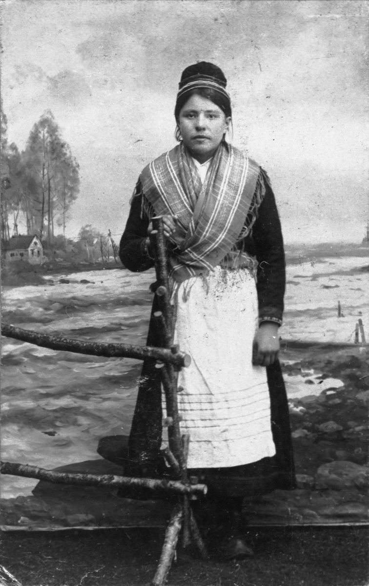 Studioportrett av en ung kvinne i samisk drakt.