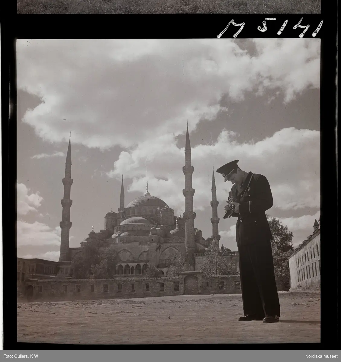 1717/L Istanbul allmänt. En turistande man i uniform fotograferar med sin kamera framför en moské.