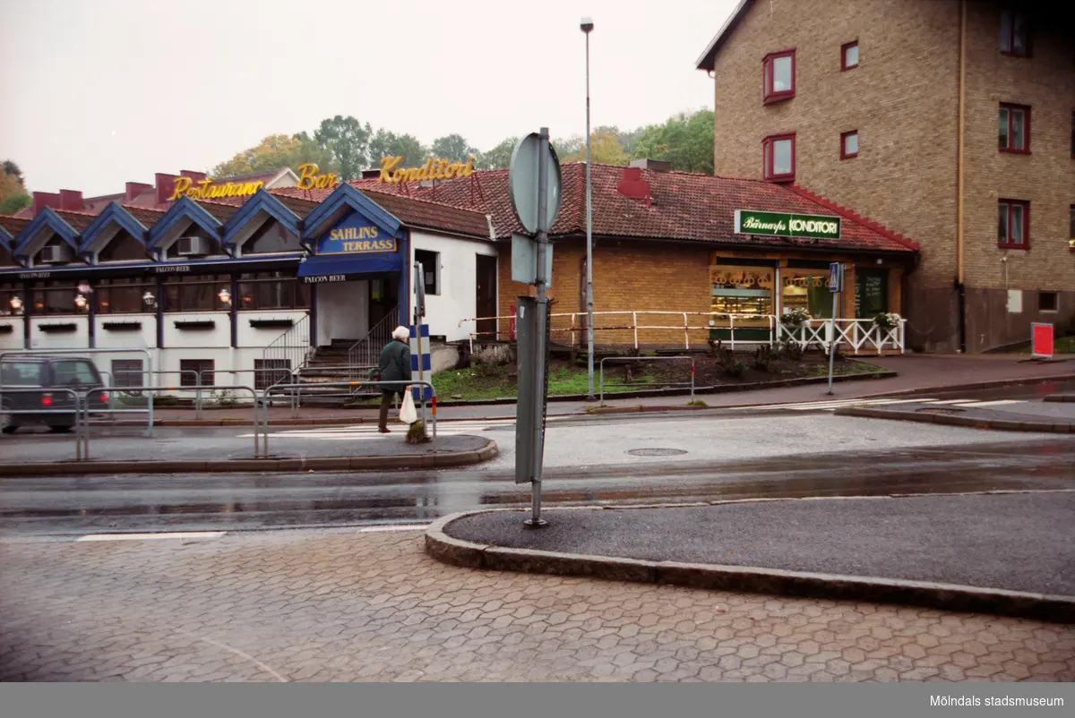 Sahlins terrass till vänster och Sahlins konditori (f.d Gunnars konditori) till höger på Storgatan/Frölundagatan. Mölndalsbro i dag - ett skolpedagogiskt dokumentationsprojekt på Mölndals museum under oktober 1996. 1996_1153-1171 är gjorda av högstadieelever från Kvarnbyskolan 9D, grupp 2. Se även 1996_0913-0940.