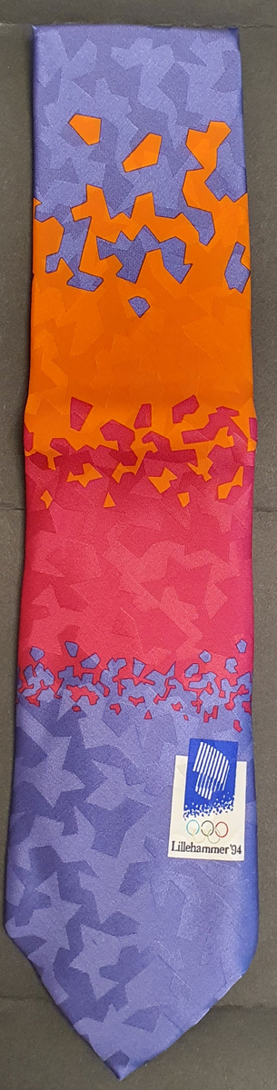 Silkeslips i original embalasje. Oransje, rosa og blått med krystallmønster i overgangene mellom fargene. Emblem for Lillehammer '94.