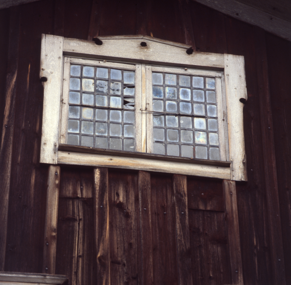 Två äldre fönster med hasp på en byggnad. Båda fönsterglasen består av många små rutor. Troligtvis blyfönster.