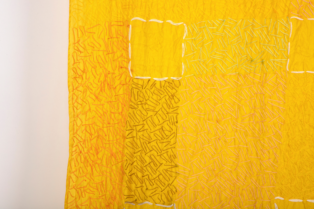 Rektangulært tekstil i gul silke, håndbrodert med silketråd i ulike farger.