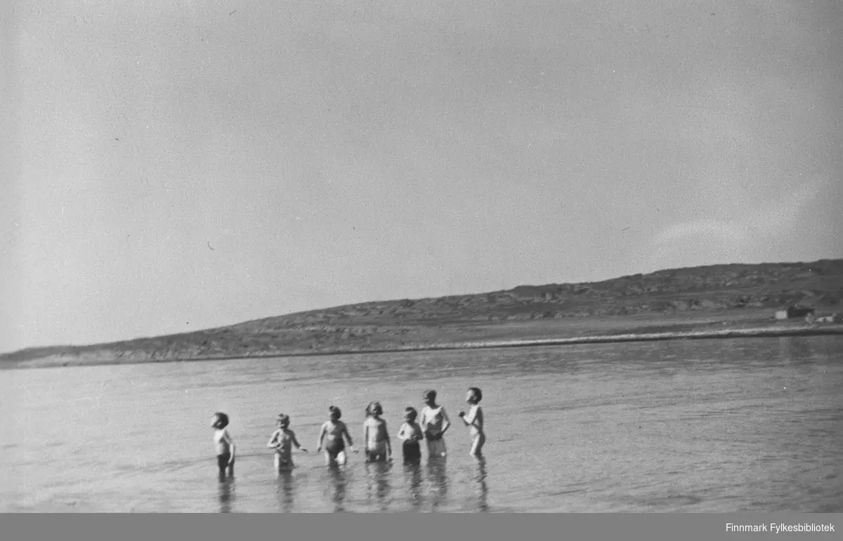 Syv barn vasser og bader i vannet en varm sommerdag i Kiberg.