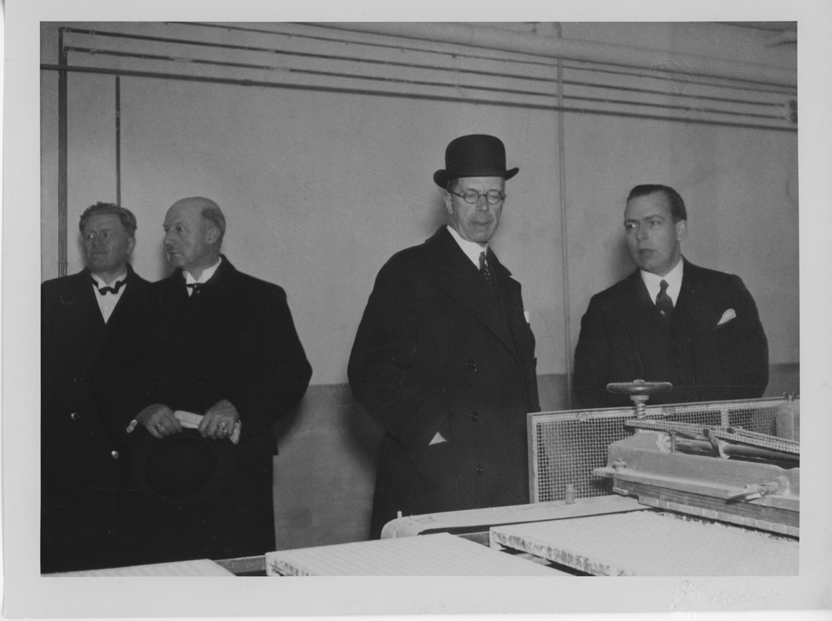 Från vänster, okänd, landshövding Sven Lybeck, kronprins Gustaf Adolf, konsul Bengt Ahlgren vid gjutmaskinen 1935. Vid kronprinsparets besök 1935.