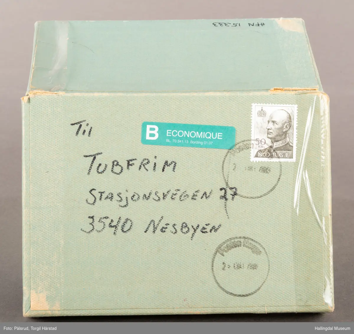Samleeske i papp, for innsamling av frimerker til Nasjonalforeningen for folkehelse / Tubfrim. Boksen har et "henglset" lokk som sitter fast på den ene langsiden. Den er trekt i et lyst turkis papir. På lokket står det adressen til Tubfrim med et stemplet frimerke fra 1992 av Kong Harald V.