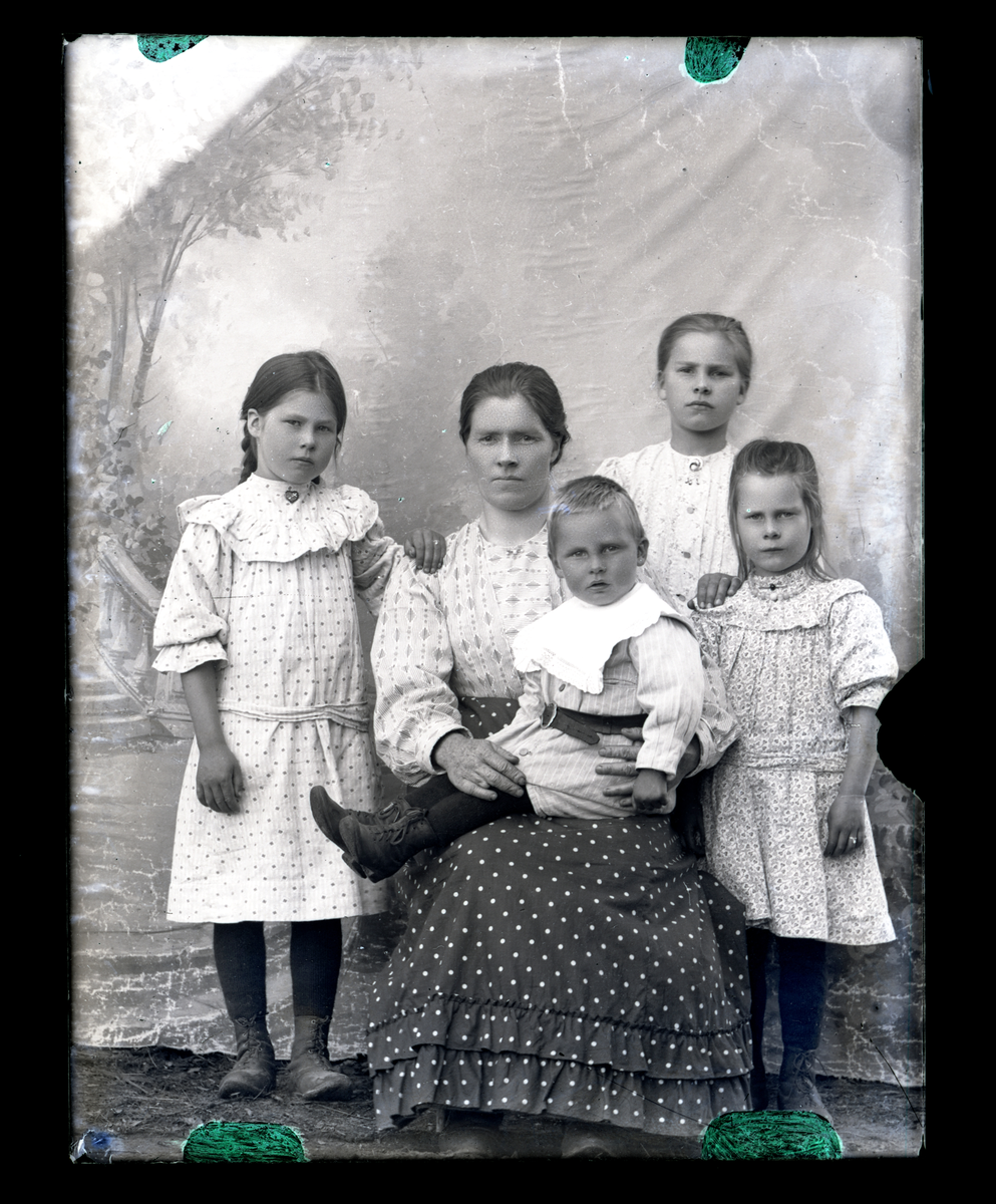 Atelierfoto. En kvinne med 4 barn i forskjellige lder (mor og barn?).