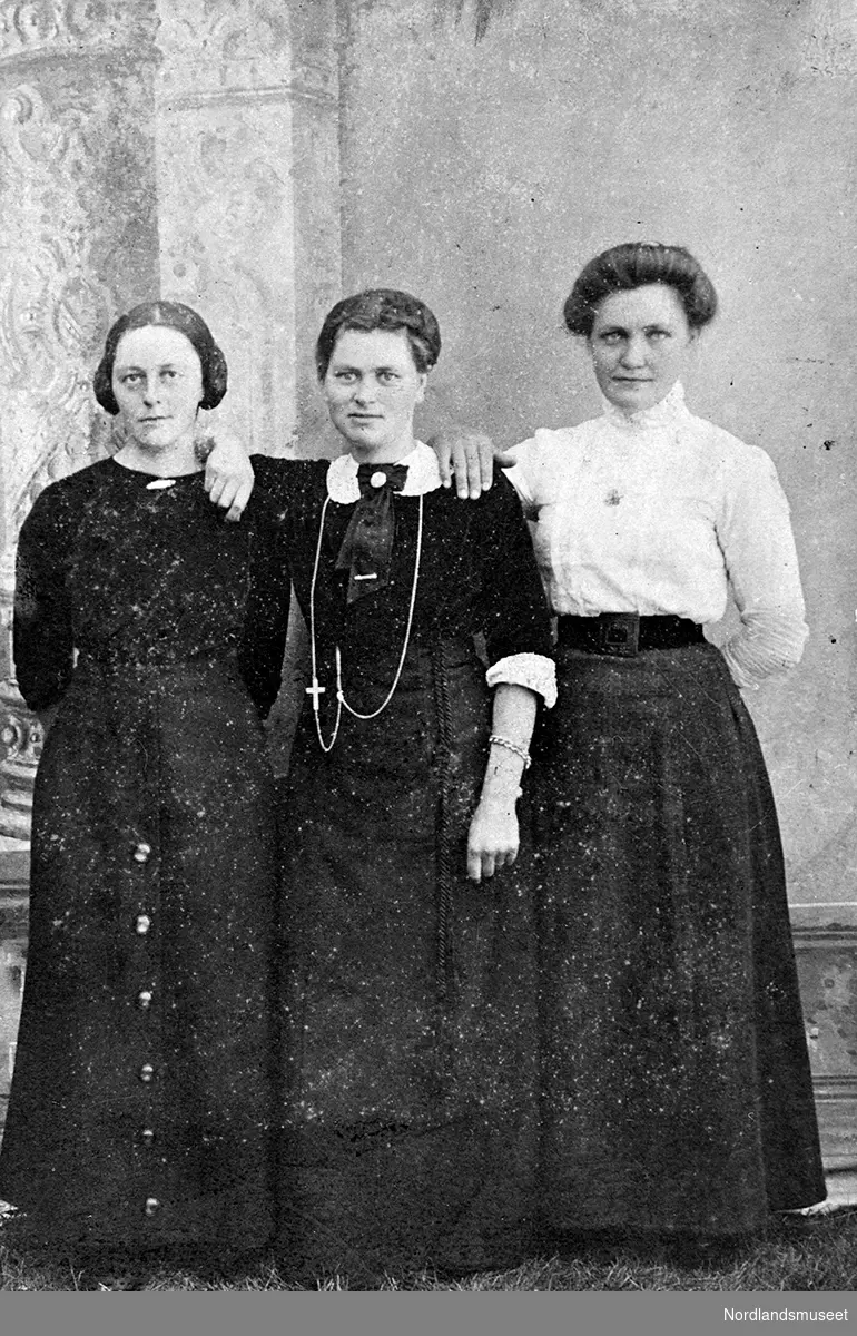 Tre damer. Damen til høyre har hvit bluse, damen i midten har hvit krage.