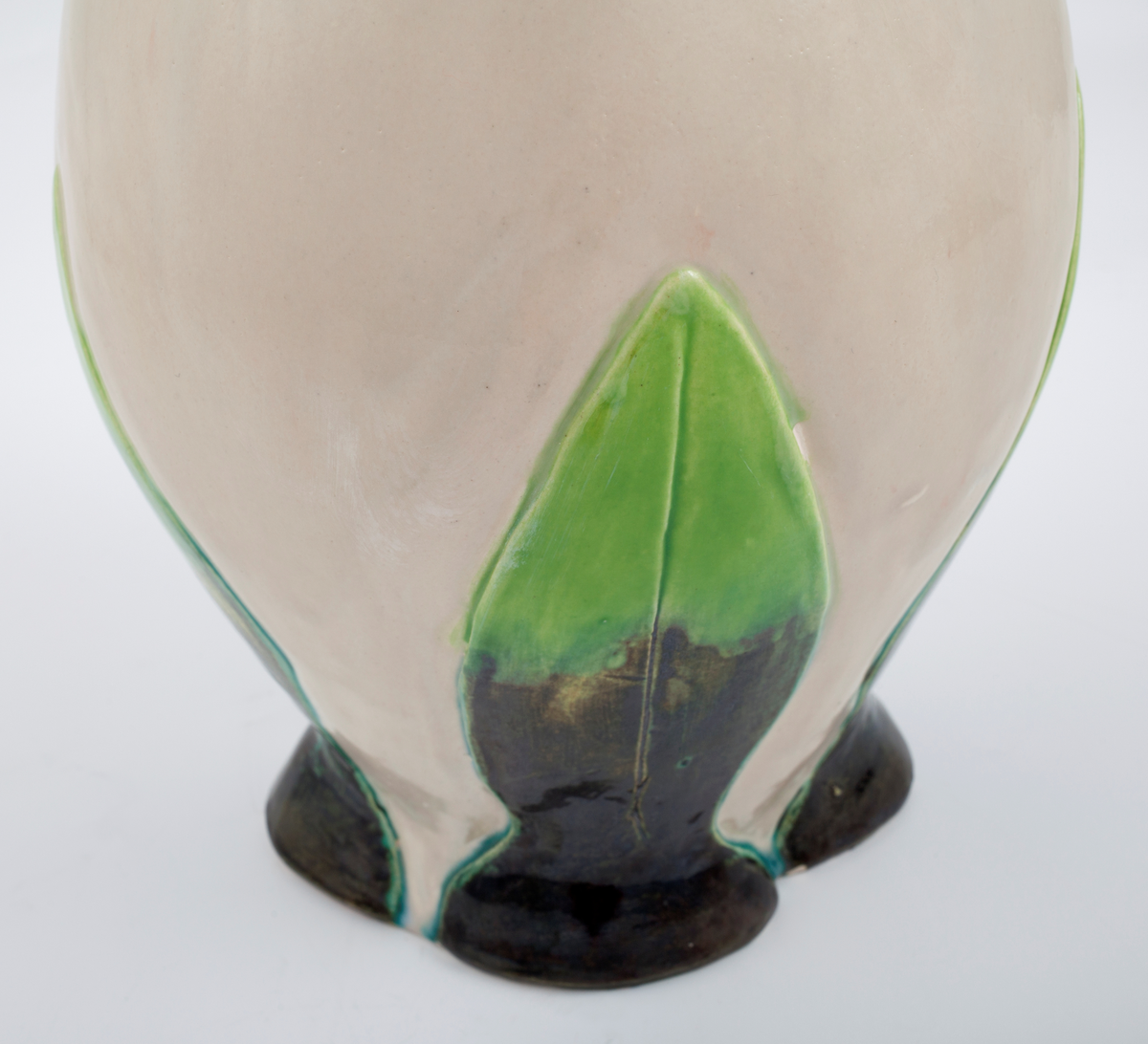 Vase i glasert steingods. Vasen er formet som en tulipan eller en lignende floral form. Toppen og bunnen av vasen har grønne blader, integrert i selve vasen. Vasen er hvit med rosa, spiralformede hanker.