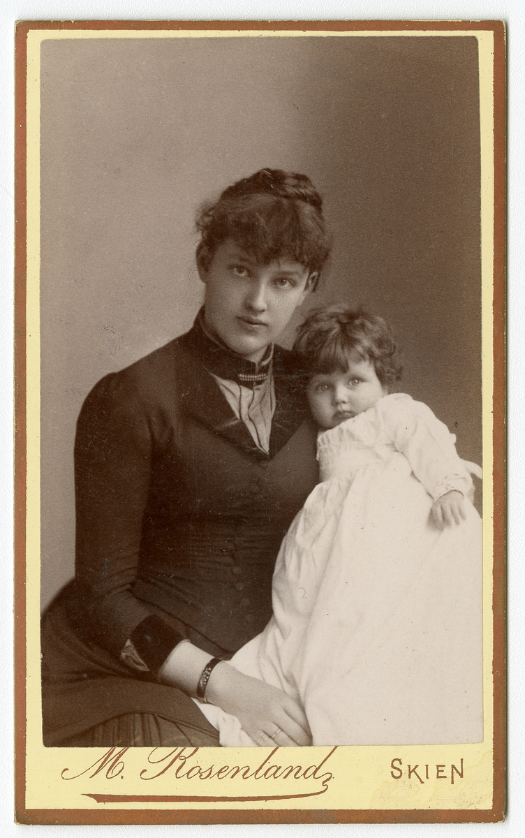 Portrettfoto av kvinne med barn. 

Trolig Nicoline Aall gift Torstensen (1862 - 1941) sammen med et av sine barn, muligens Elisabeth Thorstensen (1892)

Elisabeth arbeidet som lærer i stenografi i 1910