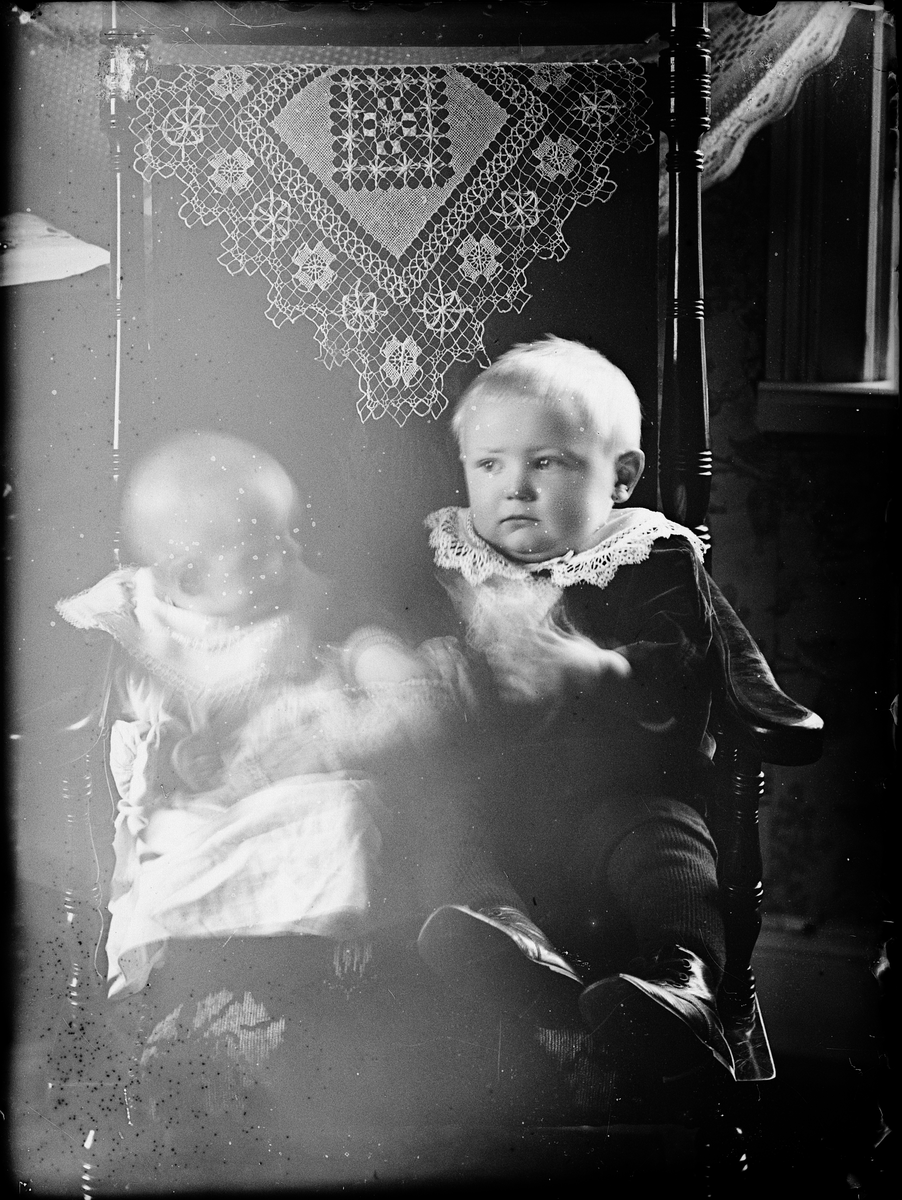 En liten pojke och spädbarn sitter i en stol, Alunda, Uppland